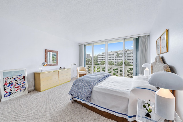 carpeted bedroom featuring a textured ceiling and floor to ceiling windows