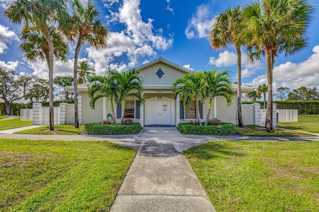 view of front facade featuring fence, a front lawn, and stucco siding