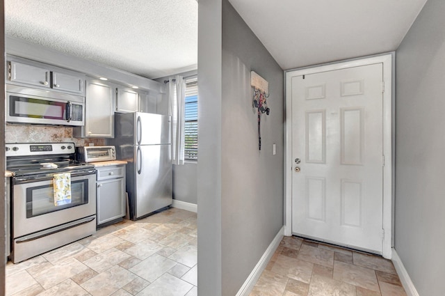 kitchen with baseboards, appliances with stainless steel finishes, and gray cabinetry