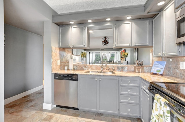 kitchen with stainless steel appliances, tasteful backsplash, a sink, light stone countertops, and baseboards