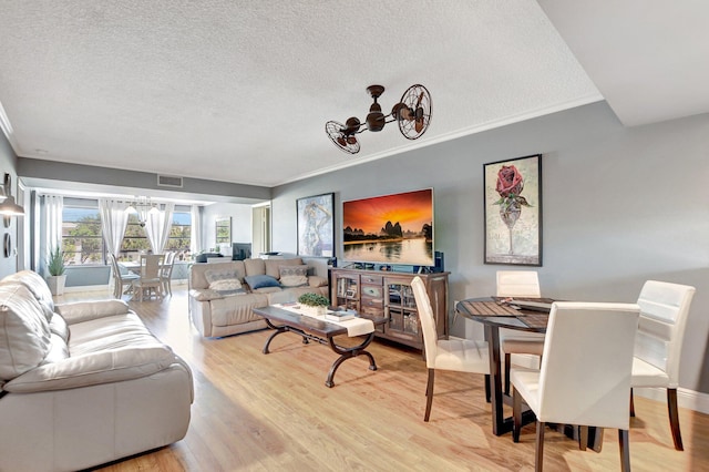 living room with crown molding, visible vents, light wood-style flooring, a textured ceiling, and a chandelier