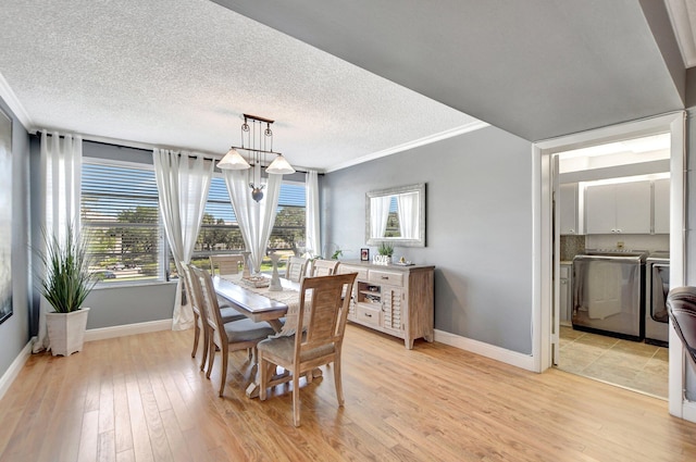 dining room featuring a textured ceiling, ornamental molding, independent washer and dryer, and light wood-style flooring