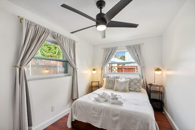 bedroom with ceiling fan, dark wood-type flooring, and multiple windows