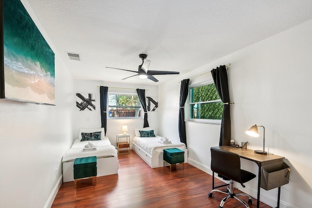 bedroom with ceiling fan, a textured ceiling, and dark wood-type flooring