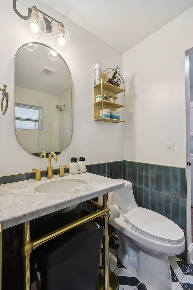 bathroom featuring toilet, vanity with extensive cabinet space, tile flooring, and tile walls