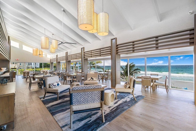 living room featuring light hardwood / wood-style flooring, beam ceiling, high vaulted ceiling, and a water view