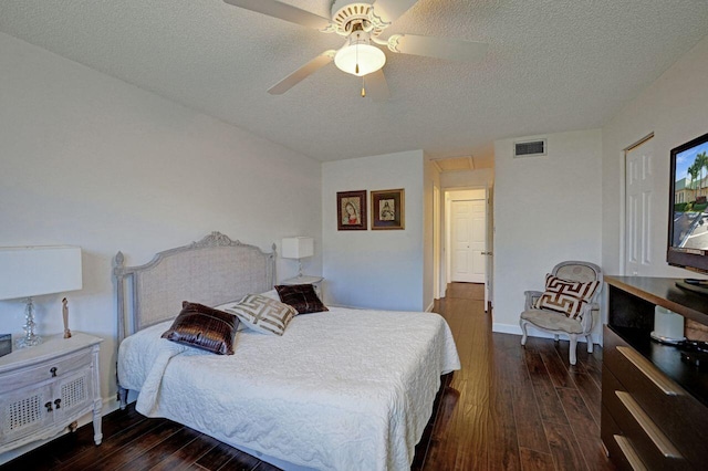 bedroom with ceiling fan, dark wood-type flooring, and a textured ceiling