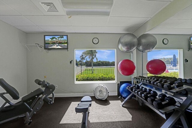 exercise room featuring a drop ceiling, visible vents, and baseboards