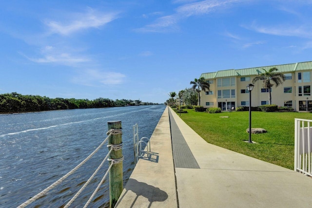 view of dock with a lawn and a water view