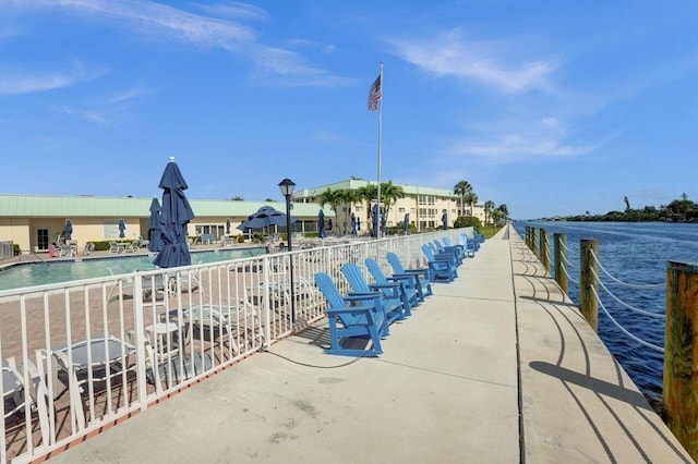 view of dock with a water view and a community pool