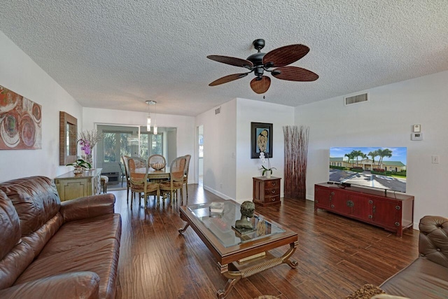 living room with a textured ceiling, dark wood-type flooring, and ceiling fan