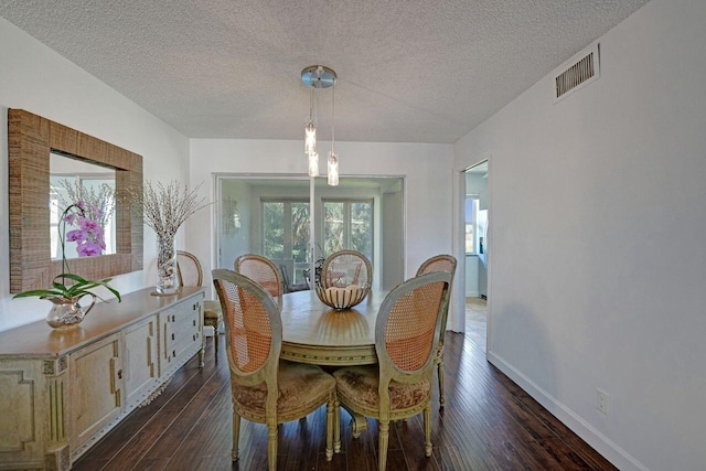 dining room with a textured ceiling, dark wood-type flooring, and a healthy amount of sunlight