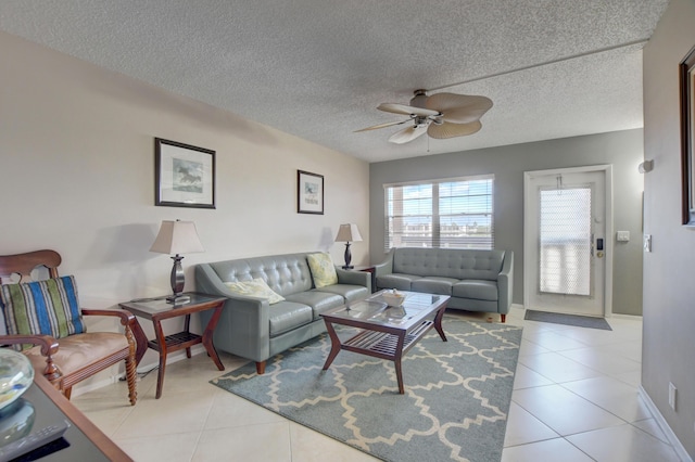 living room featuring light tile patterned floors, a textured ceiling, baseboards, and a ceiling fan