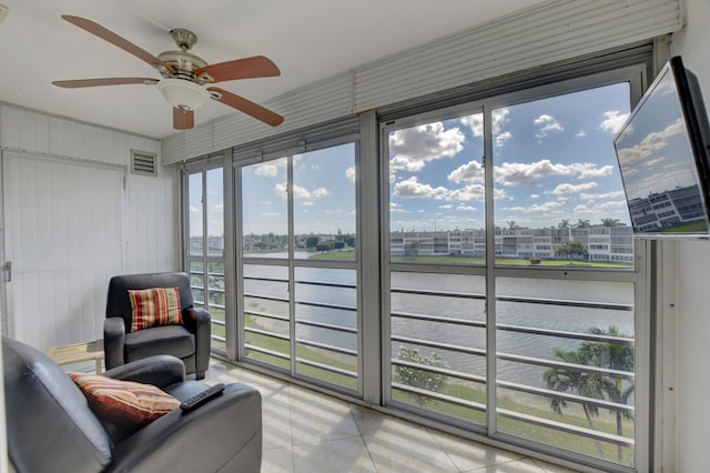 sunroom / solarium featuring a water view and ceiling fan