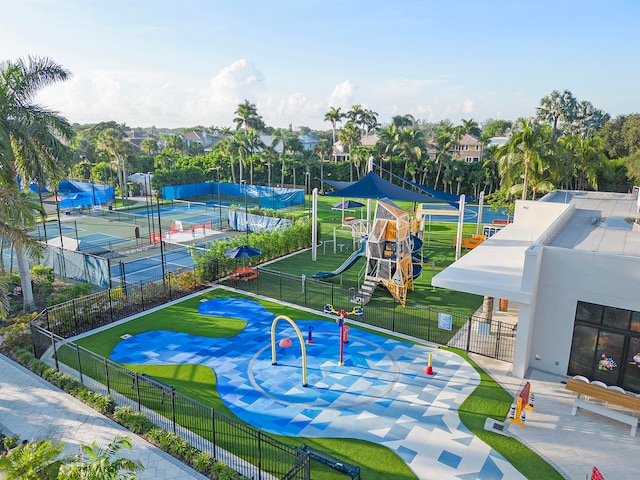 view of community featuring tennis court, a playground, and a yard