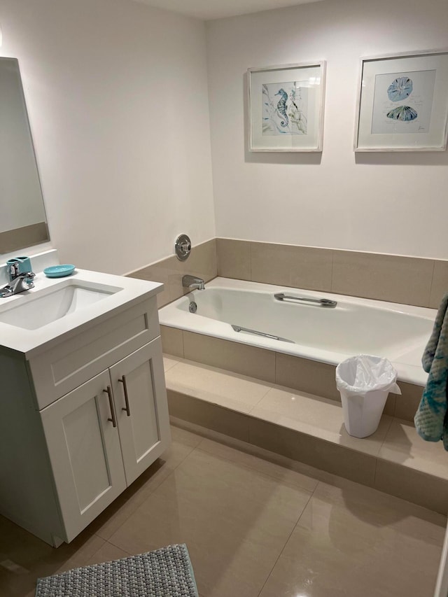 bathroom featuring tile patterned flooring, vanity, and a relaxing tiled tub