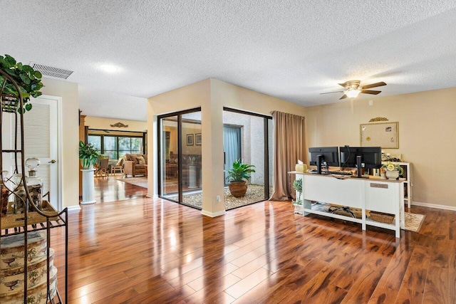 home office featuring ceiling fan, a textured ceiling, and dark wood-type flooring