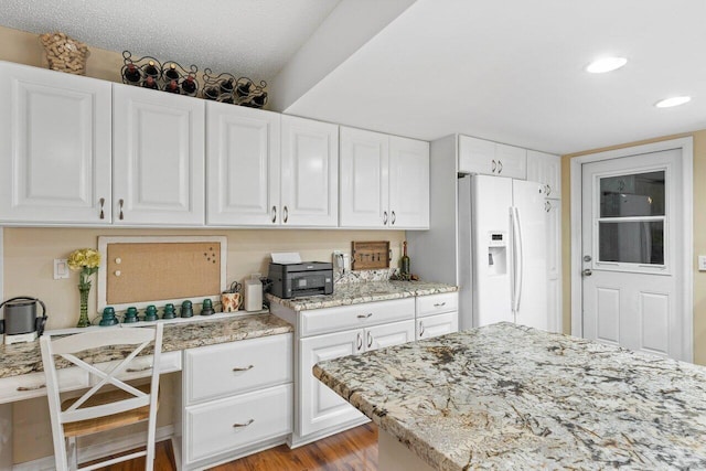 kitchen featuring light stone counters, white cabinets, light hardwood / wood-style flooring, white refrigerator with ice dispenser, and a textured ceiling