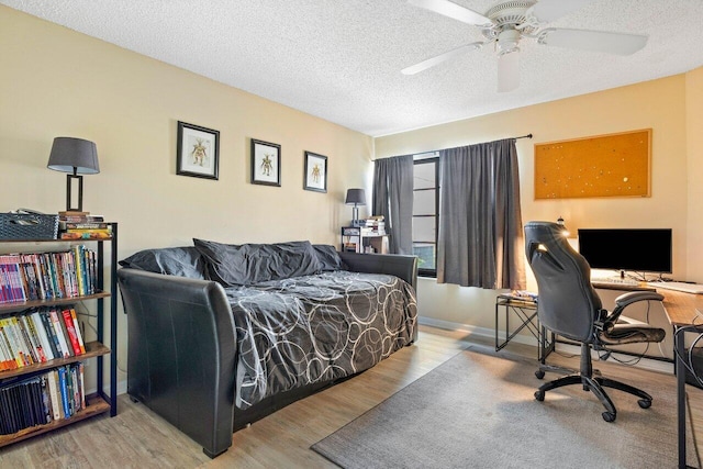 bedroom with a textured ceiling, ceiling fan, and light wood-type flooring