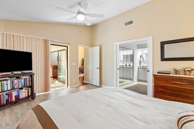 bedroom featuring connected bathroom, ceiling fan, a textured ceiling, lofted ceiling, and light wood-type flooring