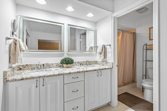 bathroom featuring toilet, tile flooring, dual vanity, and walk in shower