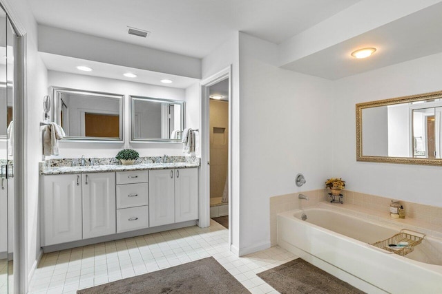 bathroom featuring tile floors, dual vanity, and a bathtub