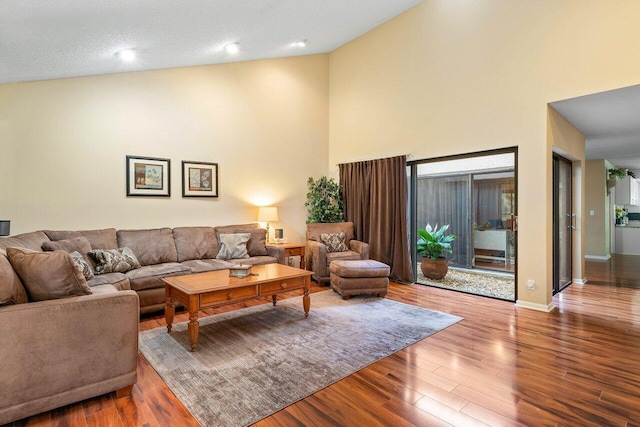 living room featuring a textured ceiling, high vaulted ceiling, and dark wood-type flooring