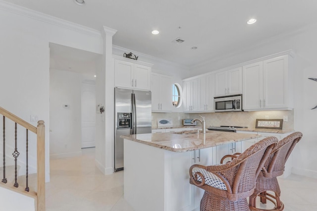 kitchen featuring sink, light stone counters, a center island with sink, white cabinets, and appliances with stainless steel finishes