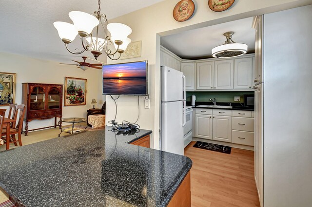 kitchen featuring ceiling fan with notable chandelier, white cabinets, kitchen peninsula, white fridge, and light wood-type flooring