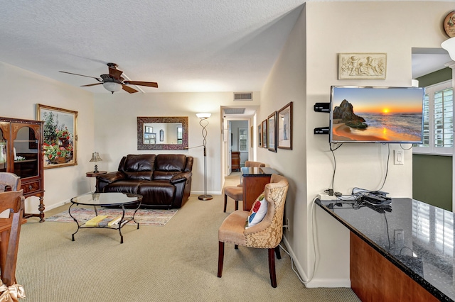 carpeted living room featuring ceiling fan and a textured ceiling