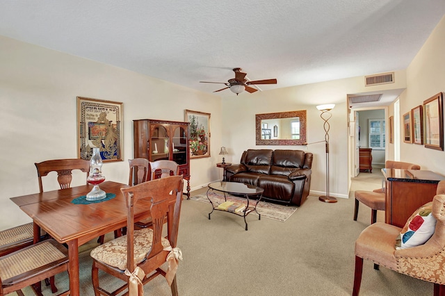 dining area with a textured ceiling, light colored carpet, and ceiling fan