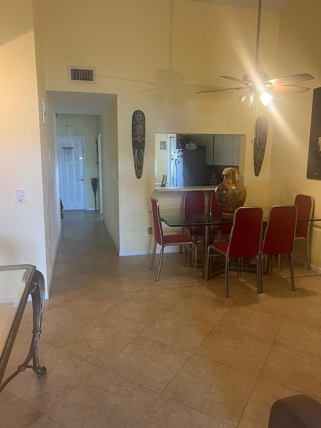 dining space featuring light tile floors, a high ceiling, and ceiling fan