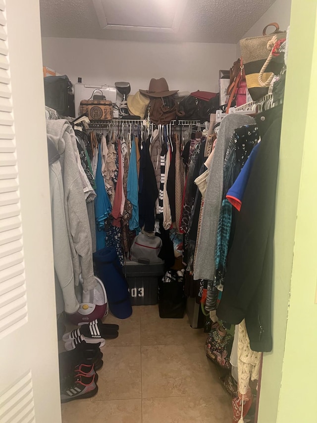 walk in closet with light tile floors