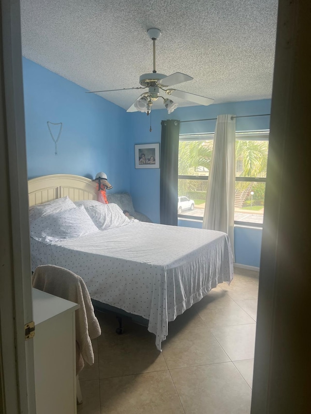 tiled bedroom featuring ceiling fan and a textured ceiling