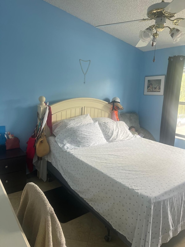 bedroom with tile flooring, ceiling fan, and a textured ceiling