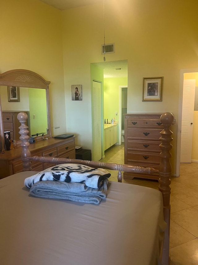 tiled bedroom with connected bathroom, a closet, and a towering ceiling