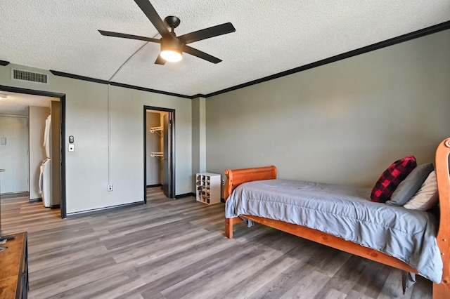 bedroom featuring a closet, ceiling fan, light wood-type flooring, a textured ceiling, and a spacious closet