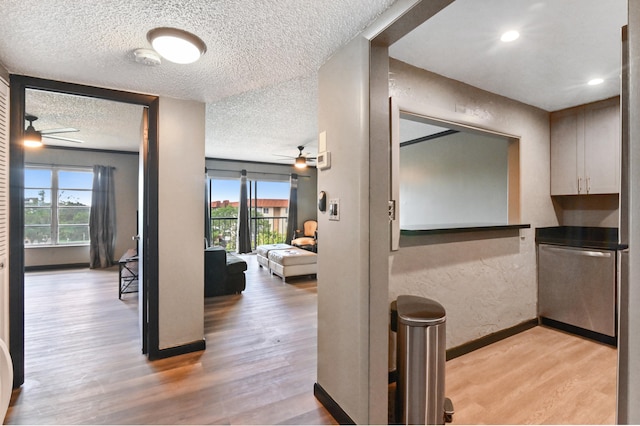 corridor with plenty of natural light, a textured ceiling, and light wood-type flooring