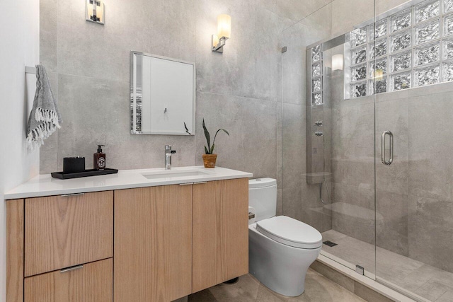 bathroom featuring vanity, tile walls, toilet, and a shower with shower door