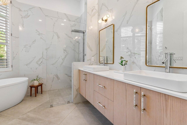 bathroom with tile walls, independent shower and bath, tile floors, and dual bowl vanity