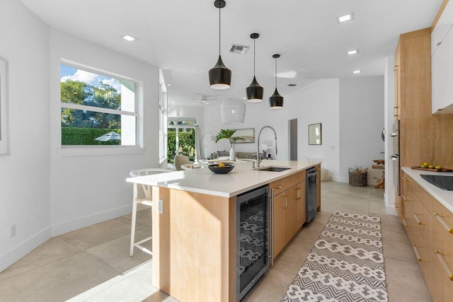 kitchen featuring a kitchen island with sink, light tile floors, sink, and beverage cooler