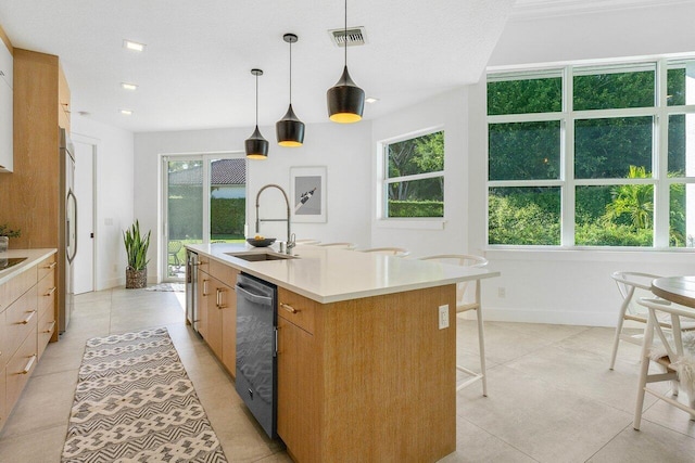 kitchen featuring sink, hanging light fixtures, an island with sink, a wealth of natural light, and light tile floors