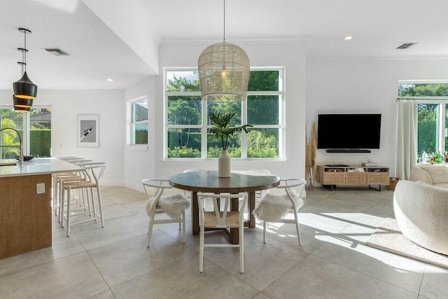 dining room with ornamental molding, a healthy amount of sunlight, sink, and light tile floors