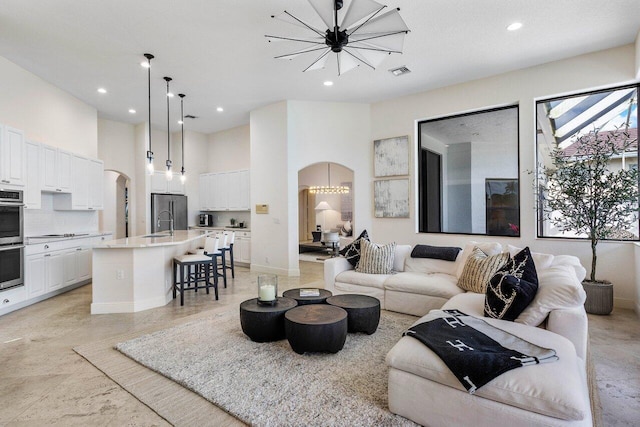 living room featuring sink, a high ceiling, and an inviting chandelier