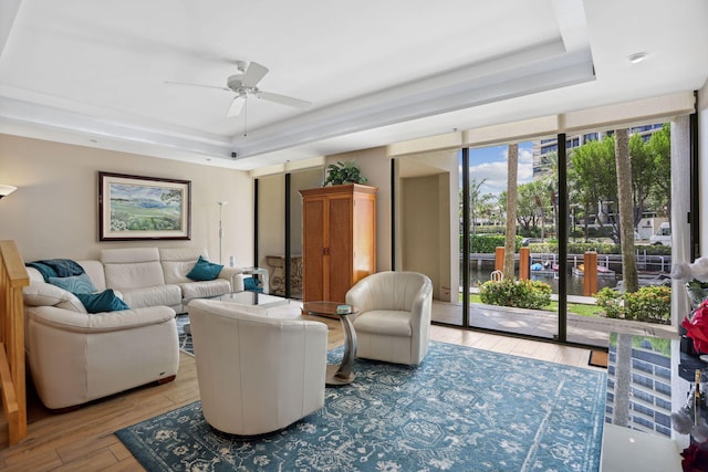 living room featuring ceiling fan, light hardwood / wood-style flooring, and a raised ceiling