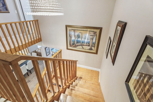 stairs featuring a towering ceiling, an inviting chandelier, and light hardwood / wood-style flooring