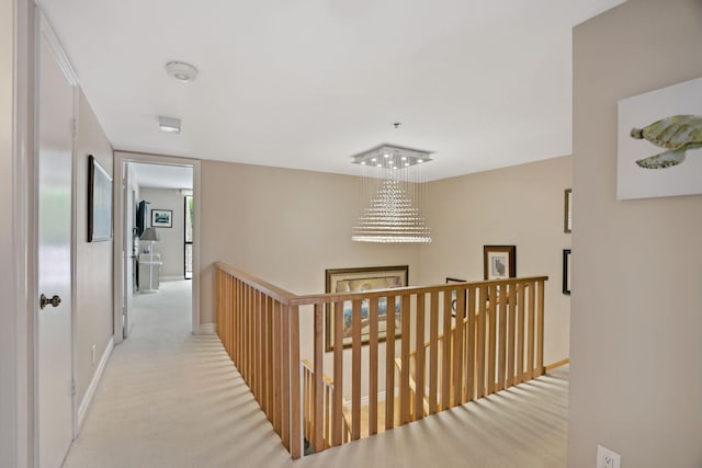 corridor with light colored carpet and an inviting chandelier