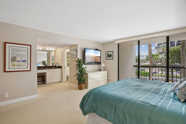 bedroom with light colored carpet, ensuite bath, and access to outside