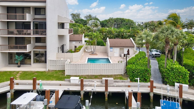 exterior space with a balcony, a patio, a fenced in pool, and a water view