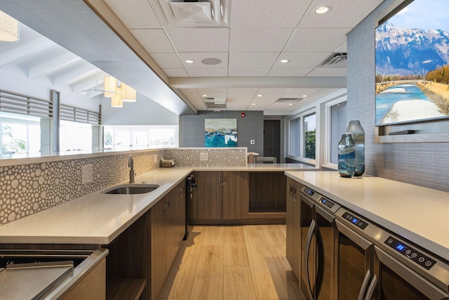 kitchen featuring a mountain view, sink, light hardwood / wood-style flooring, beam ceiling, and dark brown cabinetry